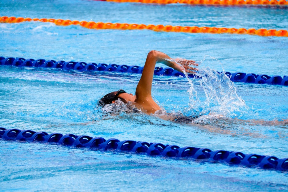 A swimmer mid-stroke between lane lines