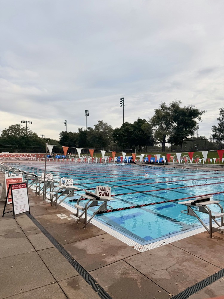 An empty competition pool deck with starting blocks and lane signage